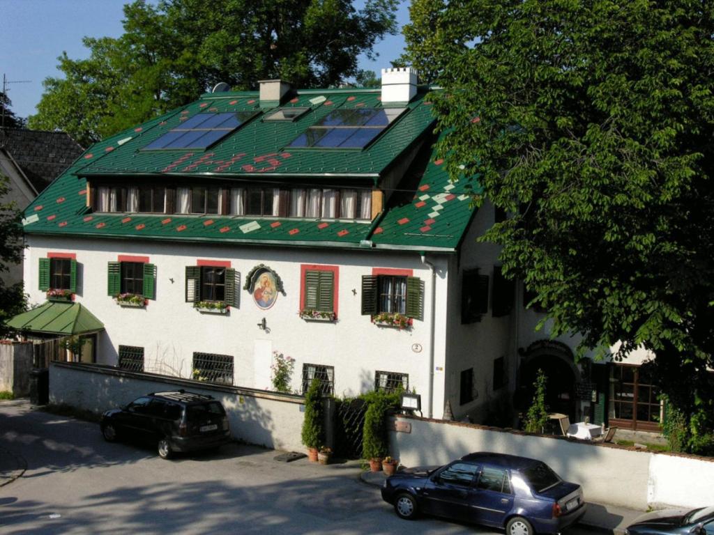 una casa con techo verde y coches aparcados delante de ella en Haus Wartenberg en Salzburgo