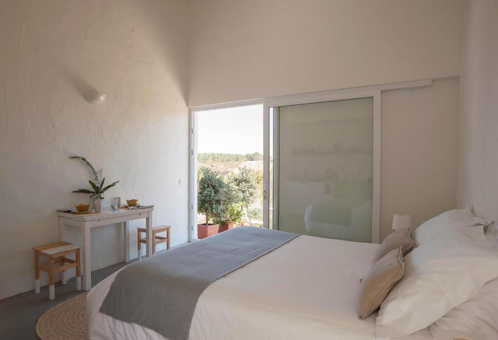 Un dormitorio con una gran cama blanca y una ventana en Alma Cheia Sunrise Studio Apartment, en Odeceixe