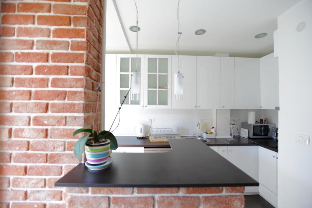 a kitchen with white cabinets and a brick wall at BRICK APARTMENT ON MACEDONIA PEDESTRIAN STREET in Skopje
