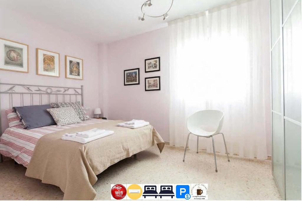 Apartamento Jardin de Santa Paula في إشبيلية: غرفة نوم بسرير وكرسي ونافذة