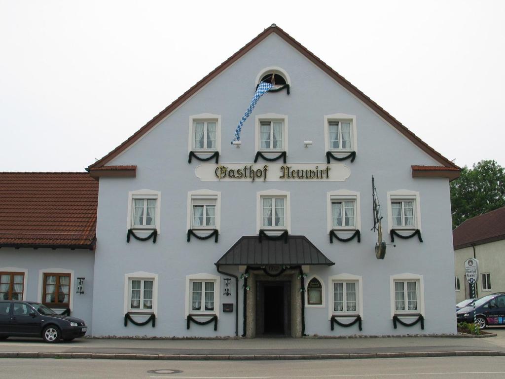 Biały budynek z znakiem na boku w obiekcie Hotel Neuwirt w mieście Hallbergmoos