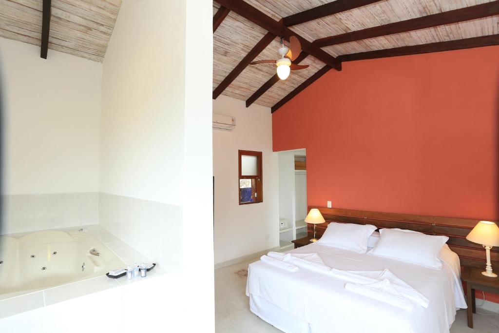 a bedroom with a large bed and a bath tub at Chalés Mariolinha in Ilhabela