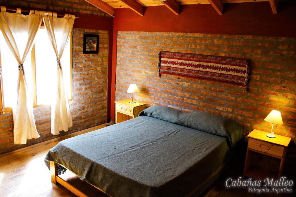 a bedroom with a bed and a brick wall at Cabañas Malleo in Junín de los Andes