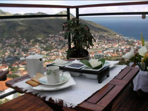 a table with plates and cups on a table with a view at Casa da Adega in Machico