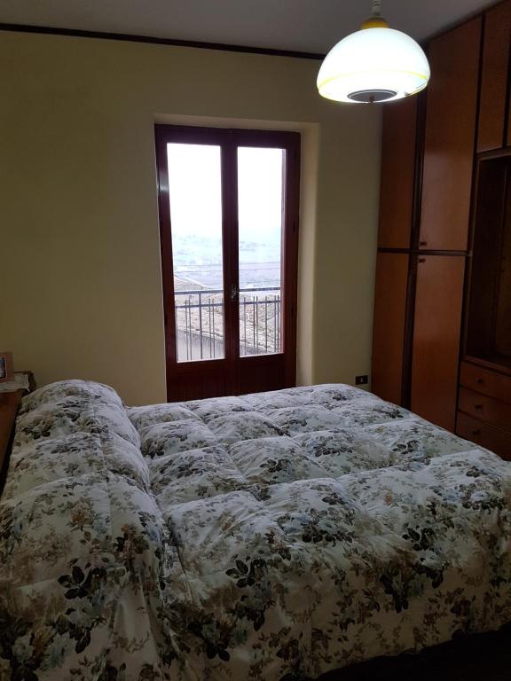 a bedroom with a bed with a floral bedspread and a window at La Nicchia di Gangi in Gangi