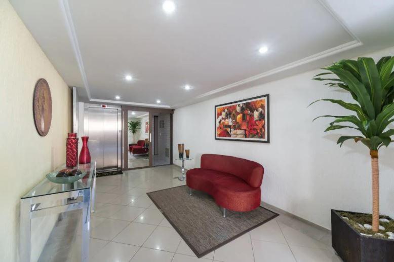 sala de estar con silla roja y maceta en Luxuoso Quarto E Sala Mobiliado, en Recife