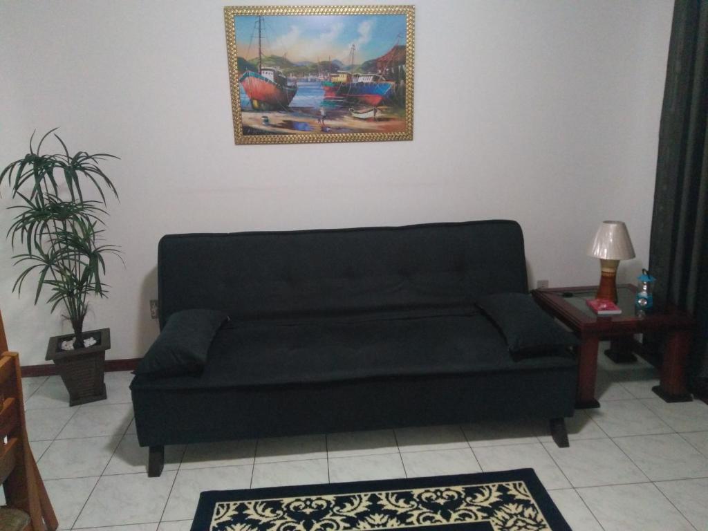 un sofá en una sala de estar con una pintura en la pared en Apartamento em Cabo Frio, en Cabo Frío