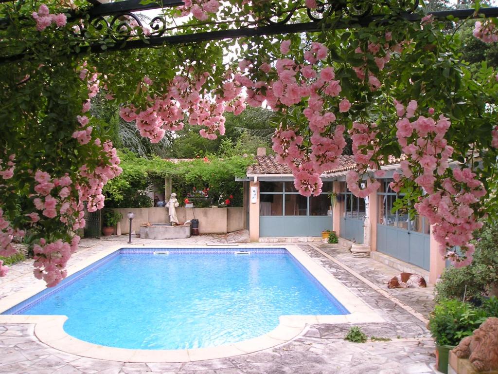 une piscine dans un jardin avec des fleurs roses dans l'établissement LES BRUYERES chambre d'hôte de charme Calme assuré, à Loupia