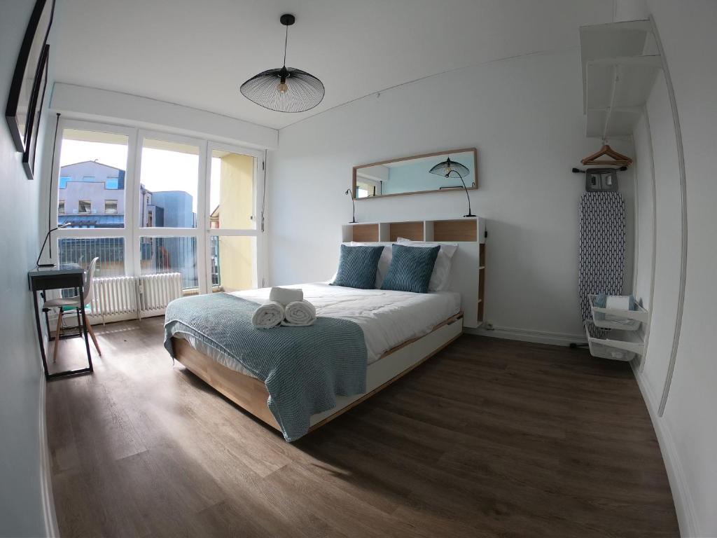 une chambre avec un grand lit et une grande fenêtre dans l'établissement Cozy Appartement Gare Pompidou, à Metz