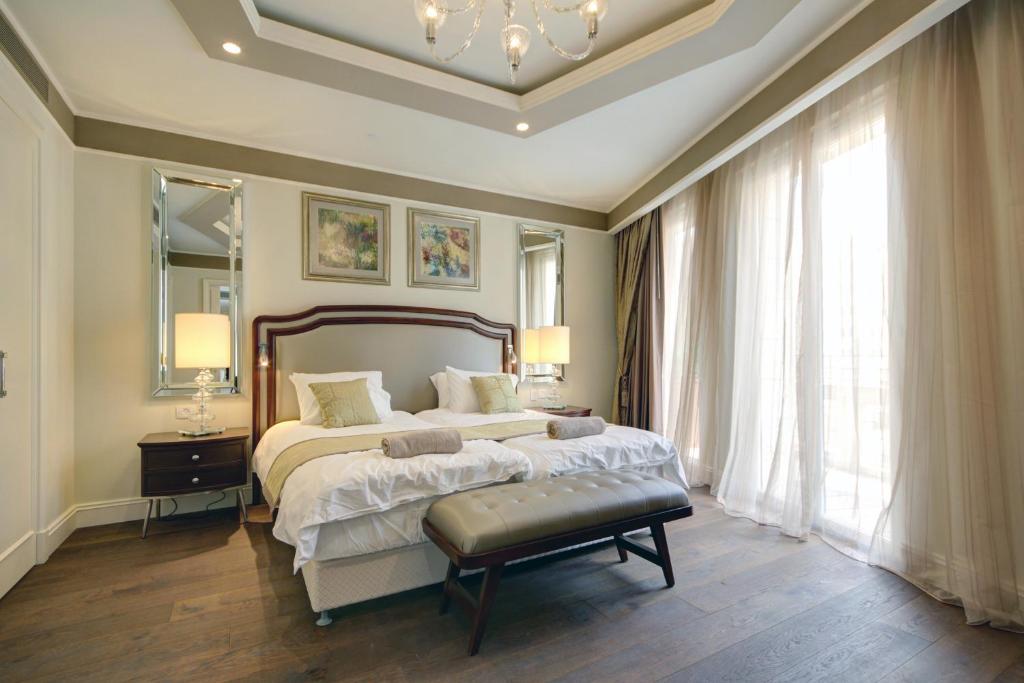 a bedroom with a large bed and a chandelier at Waldorf Astoria Residences- Rental Israel in Jerusalem