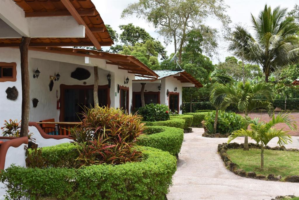 a garden in front of a house with green hedges at Piedras Blancas Lodge in Puerto Ayora