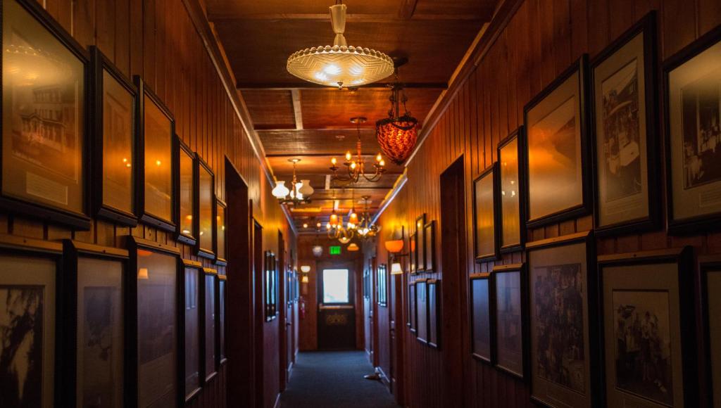 a hallway with pictures on the walls and a chandelier at McMenamins Gearhart Hotel in Gearhart