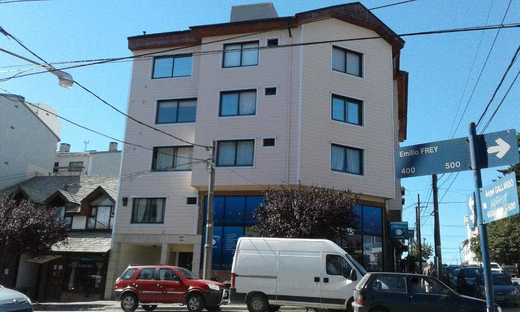 un edificio blanco alto con coches estacionados frente a él en Paraísos Del Sur en San Carlos de Bariloche