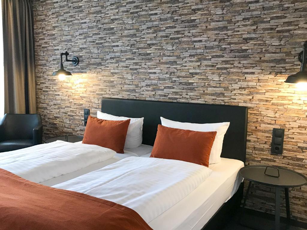 Cama grande en habitación con pared de ladrillo en Trend Hotel, en Oldenburg