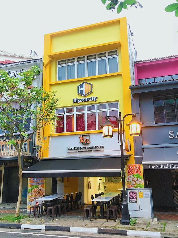 a yellow building with tables in front of it at hipstercity hostel in Singapore