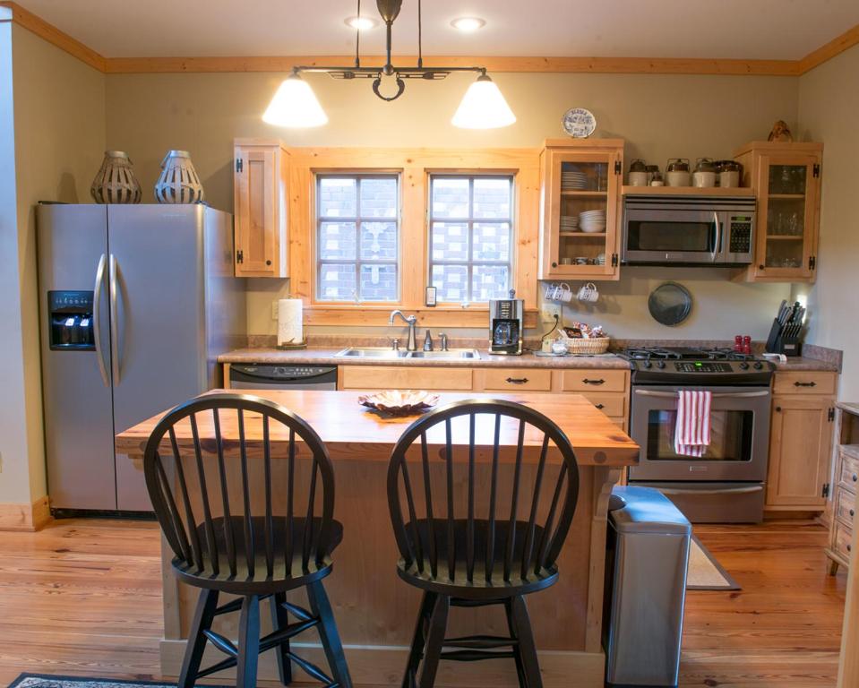 a kitchen with a refrigerator and a table with two chairs at Wayward Cottage in Pisgah