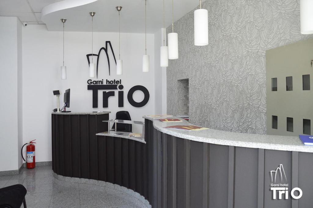 a lobby with a black and white counter with a sign at Garni Hotel Tri O in Kragujevac