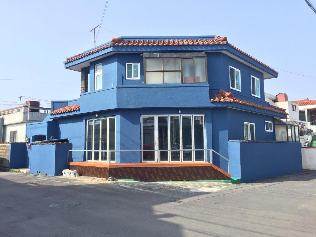 a blue and white building with a blue roof at Jeju Guesthouse in Jeju