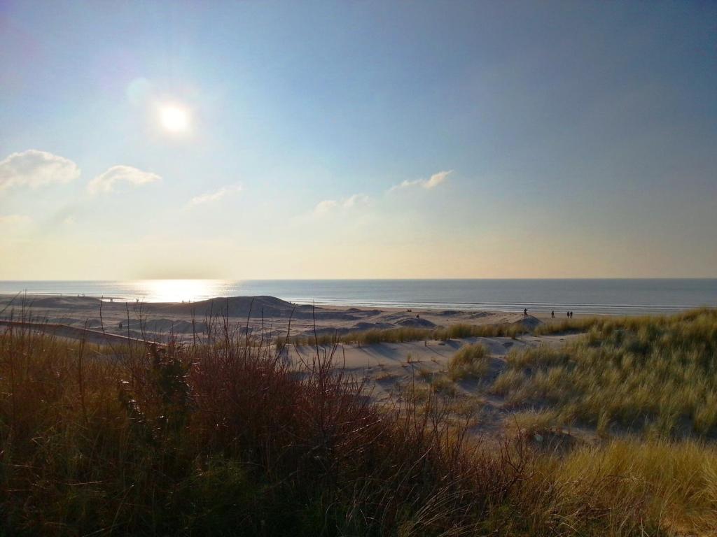 a beach with the sun setting over the ocean at Hôtel Barrière Le Westminster in Le Touquet-Paris-Plage
