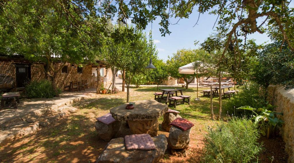 een tuin met een tafel, banken en bomen bij Hotel Rural Can Partit - Adults Only in Santa Agnès de Corona