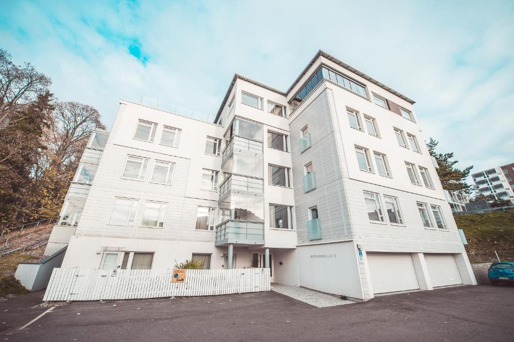 a white apartment building with a parking lot at Forenom Serviced Apartments Espoo Leppävaara in Espoo