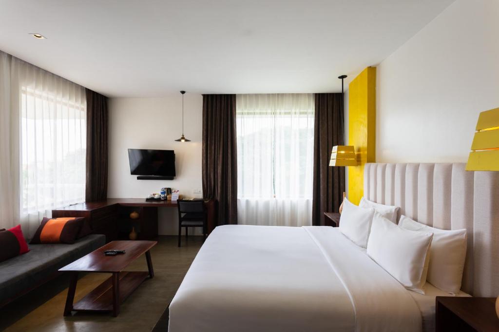 a hotel room with a large white bed and a couch at Apsara Residence Hotel in Siem Reap