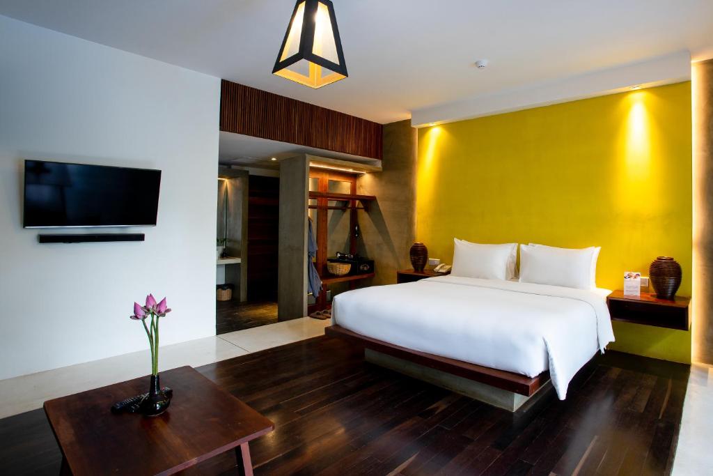 a bedroom with a white bed and a yellow wall at Apsara Residence Hotel in Siem Reap