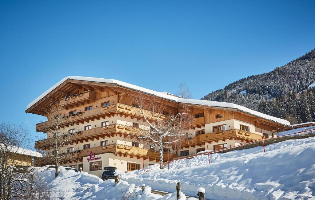 a building in the snow with a train in front at Johanneshof - Dein MOUNTAIN Wohlfühlhotel in Saalbach-Hinterglemm