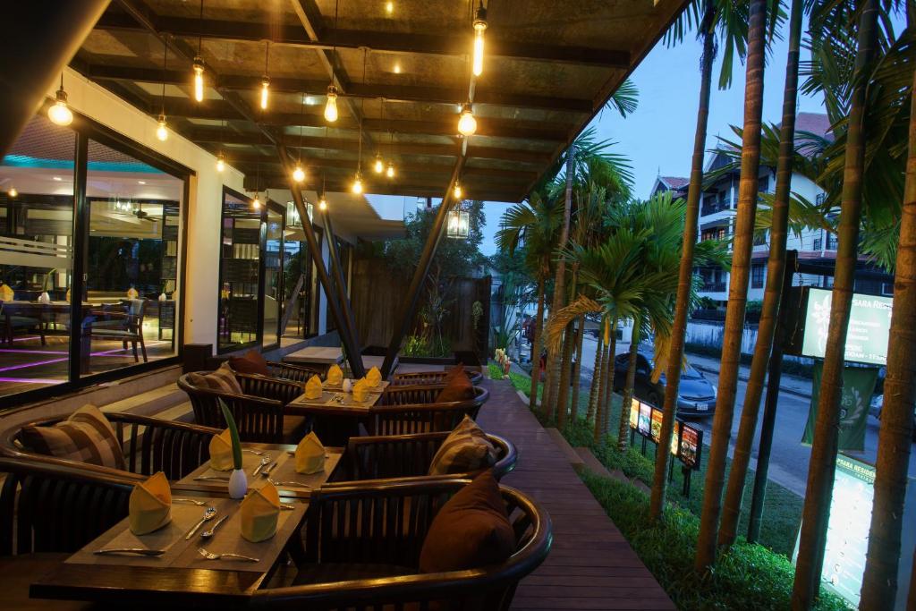 a restaurant with tables and chairs and palm trees at Apsara Residence Hotel in Siem Reap