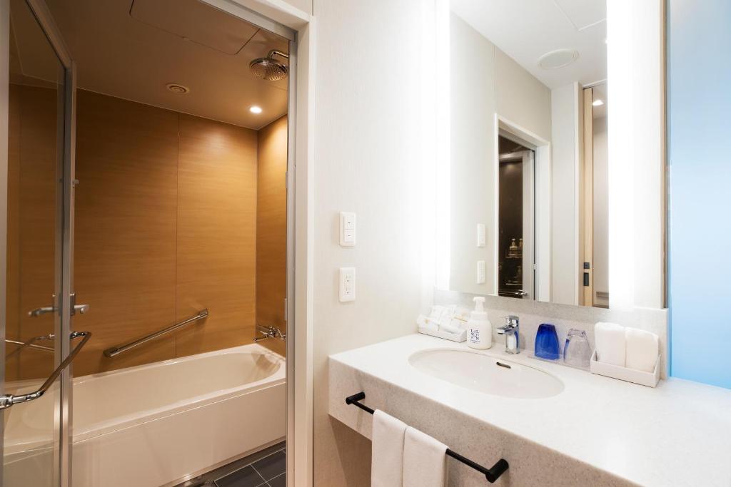 a bathroom with a sink and a bath tub at Centrair Hotel in Tokoname