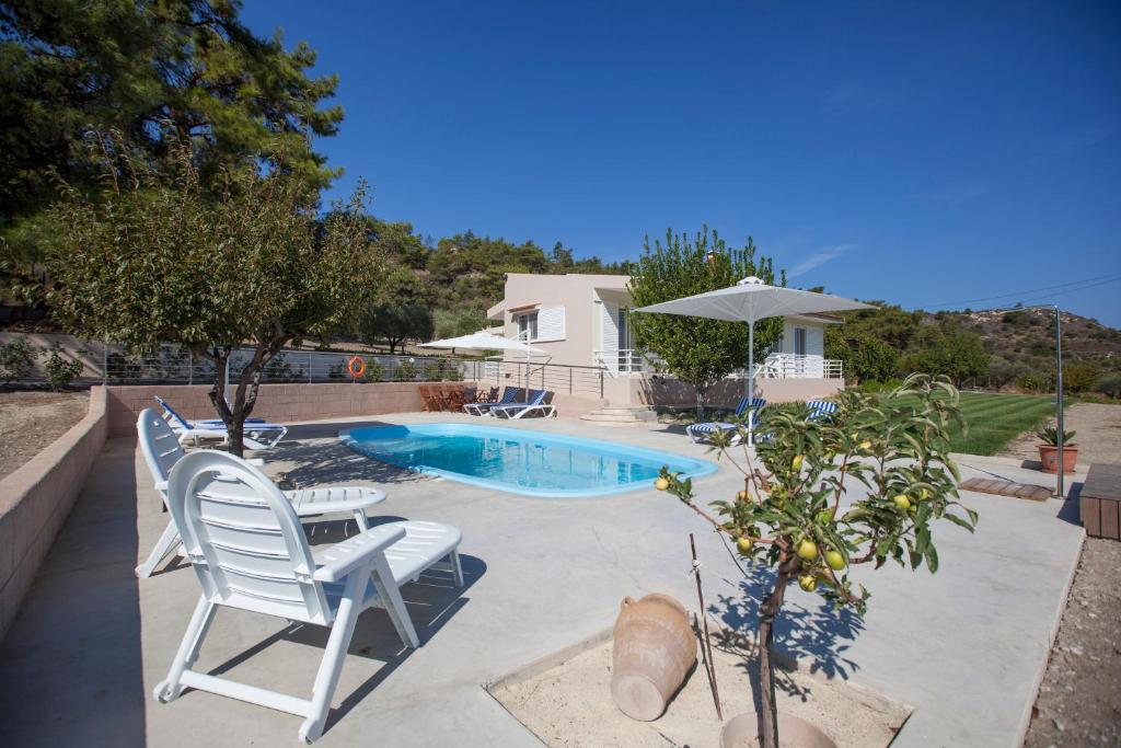 a swimming pool with two chairs and an umbrella at The Olive Grove Villa Private Pool with star links WiFi in Theologos