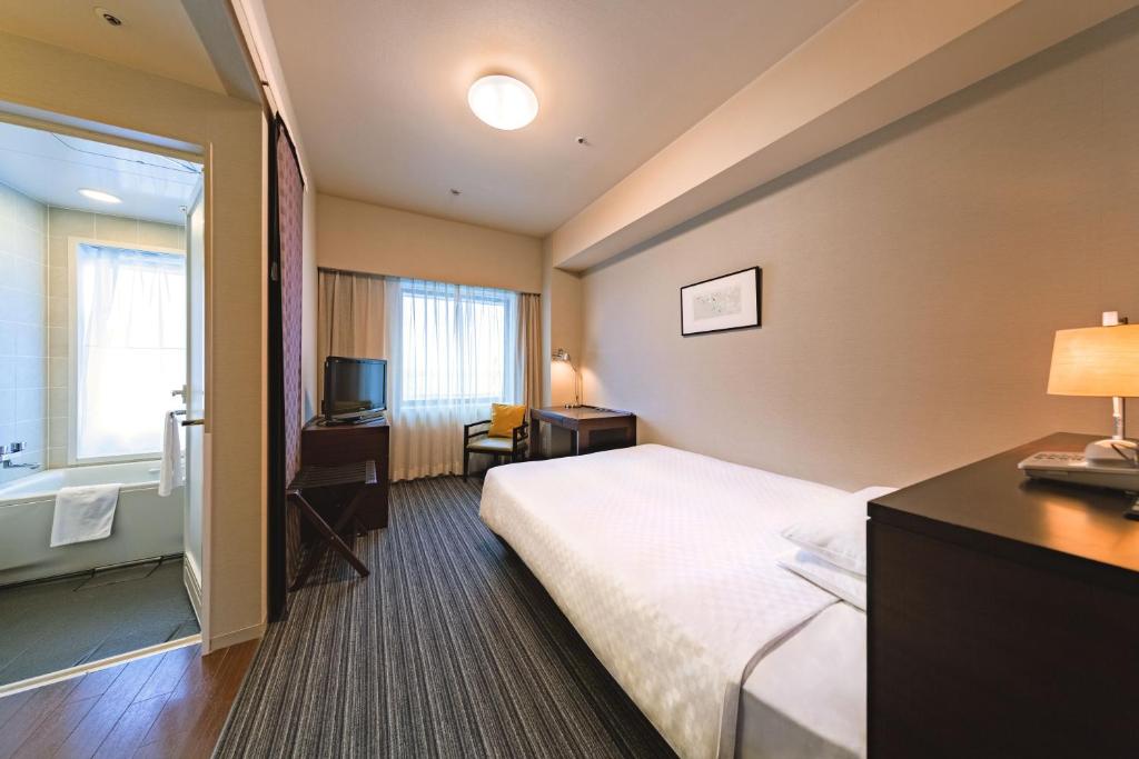 a hotel room with a bed and a bathroom at Centrair Hotel in Tokoname