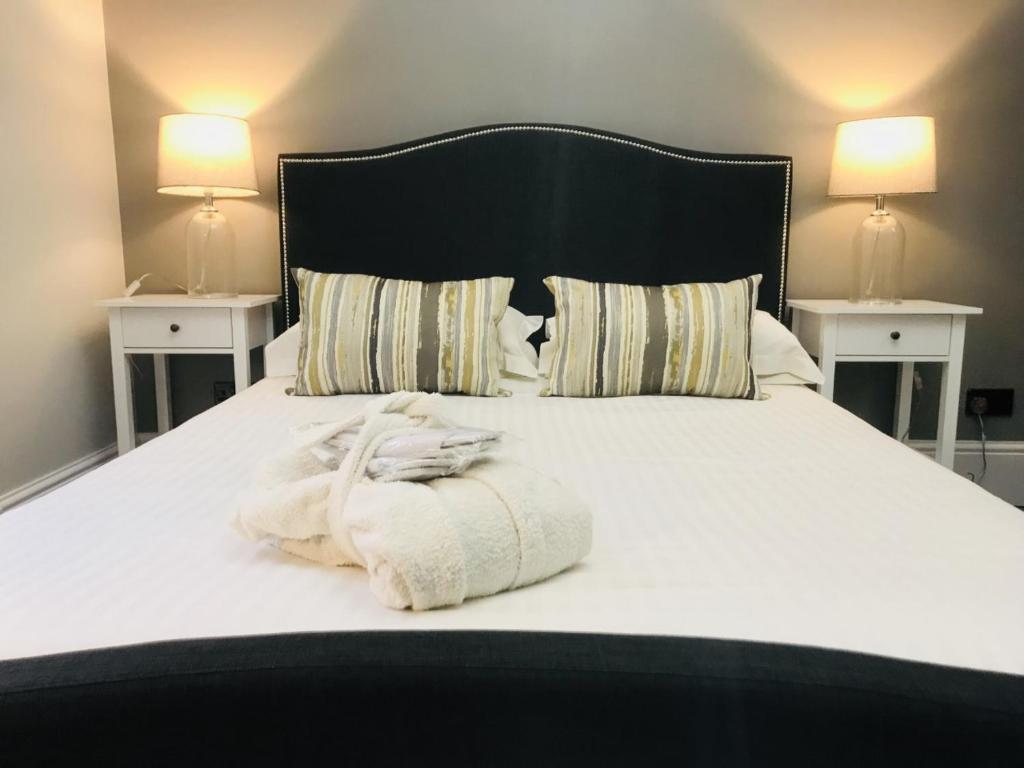 a bed with a white towel on it with two night stands at Cambridge Villa in Warwick