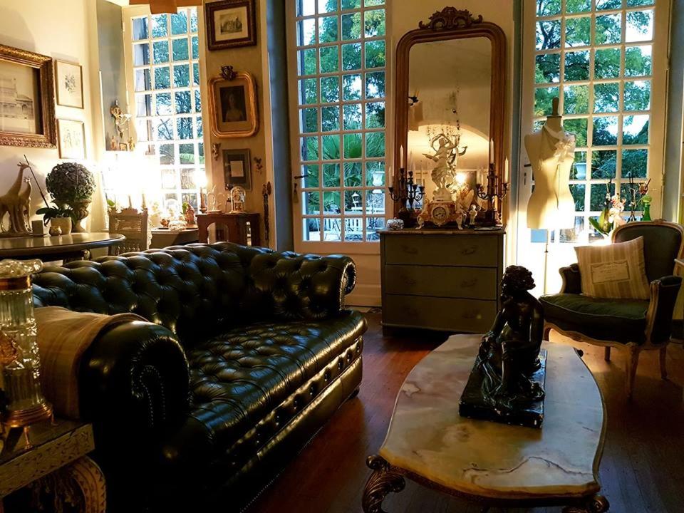 a living room with a leather couch and a mirror at La Villa des Remparts in Labastide-dʼArmagnac