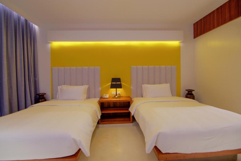two beds in a room with a yellow wall at Apsara Residence Hotel in Siem Reap