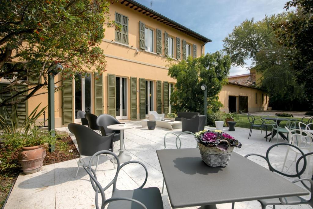 een patio met een tafel en stoelen en een gebouw bij Corte livia Room & Breakfast in Forlì