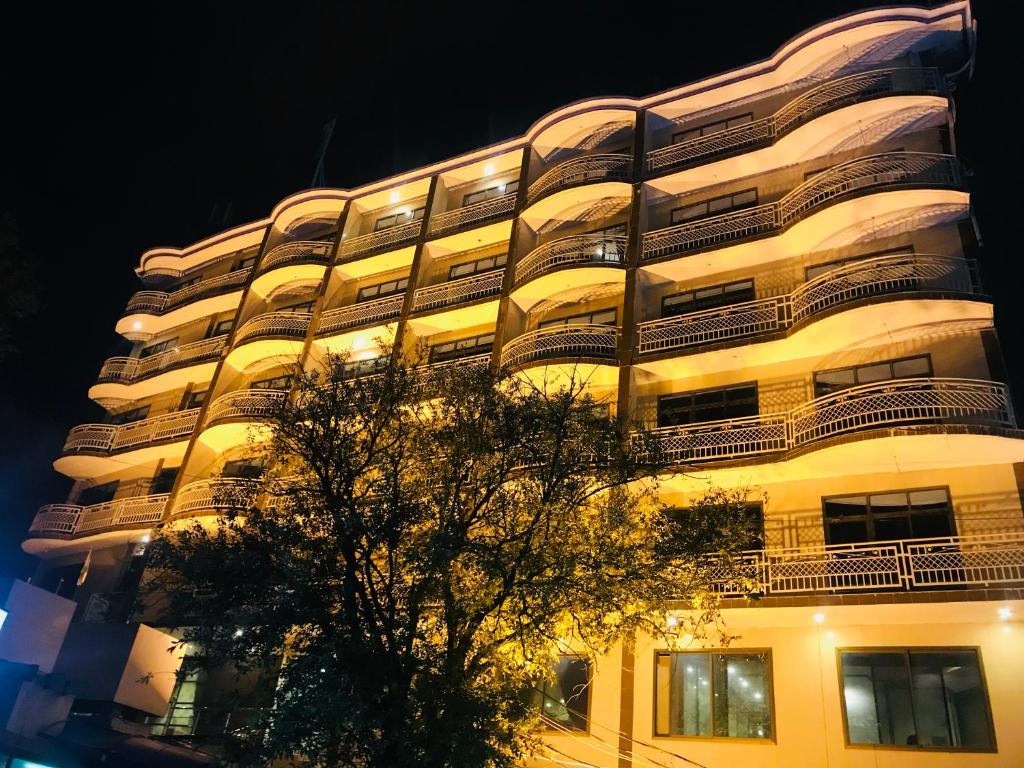 a tall white building with a tree in front of it at Hotel One Mall Road Murree in Murree