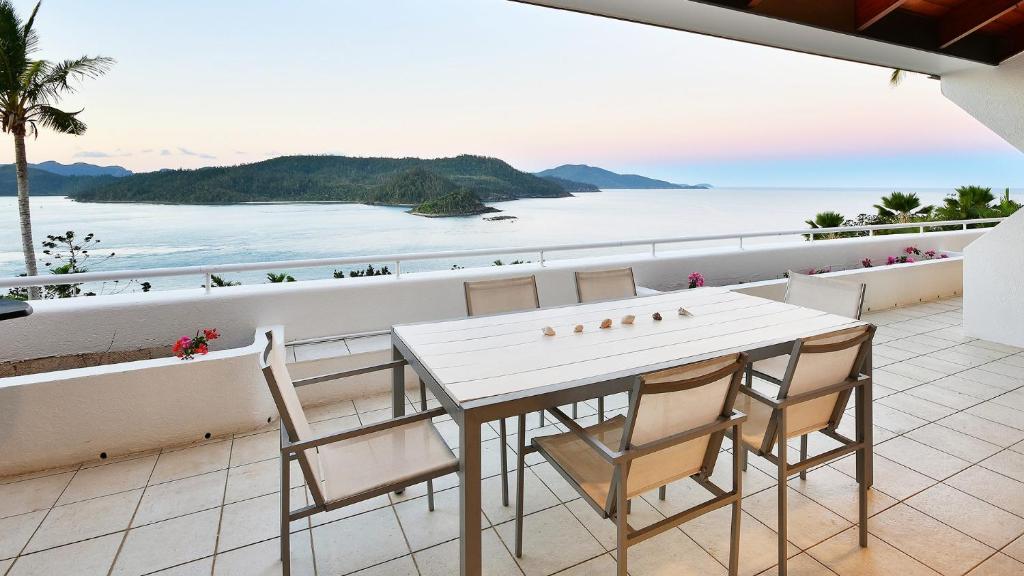 a table and chairs on a balcony with a view of the ocean at Bella Vista E9 - Ocean View Spacious 2 Bedroom with golf buggy in Hamilton Island