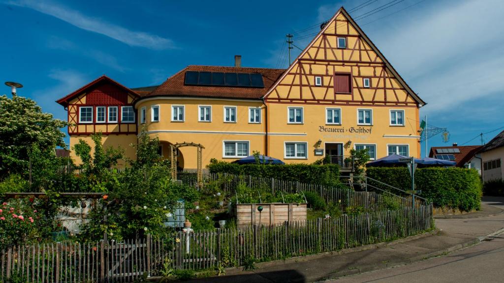 a yellow house with a fence in front of it at Brauerei und Gasthof zum Engel in Waldstetten