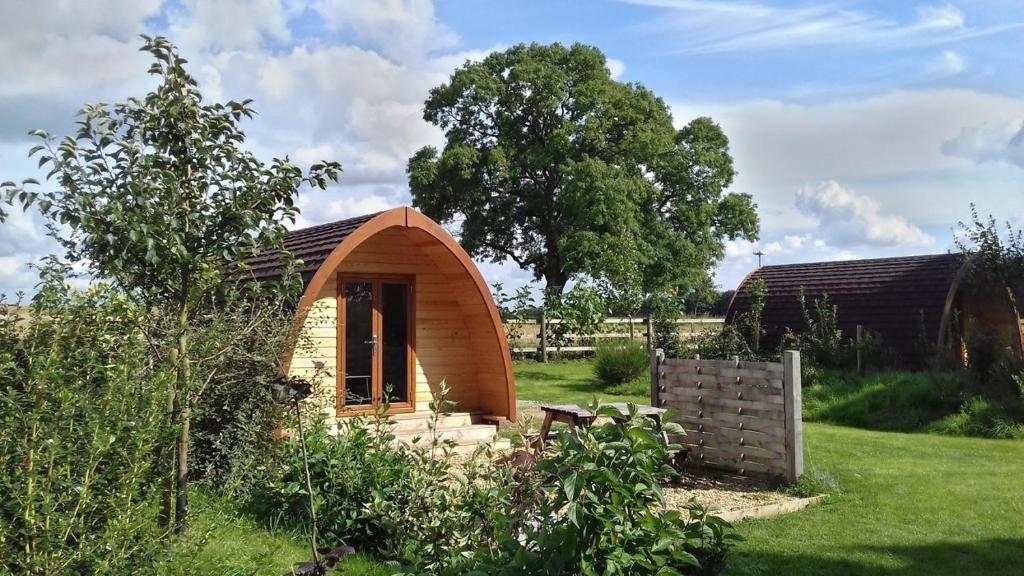 una pequeña casa de madera en un campo de hierba en Campion Glamping Pod, en Cheltenham