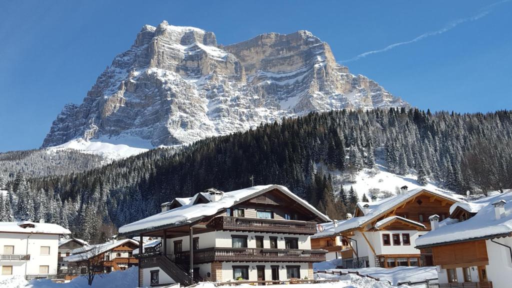 Casa Piva Dolomiti في فال دي زولدو: جبل مغطى بالثلج أمام مدينة بها بيوت