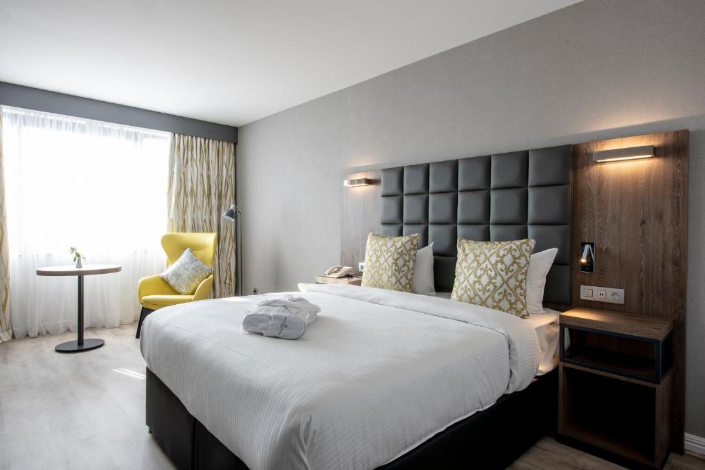 a hotel room with a large bed and a chair at Gresham Belson Hotel Brussels in Brussels