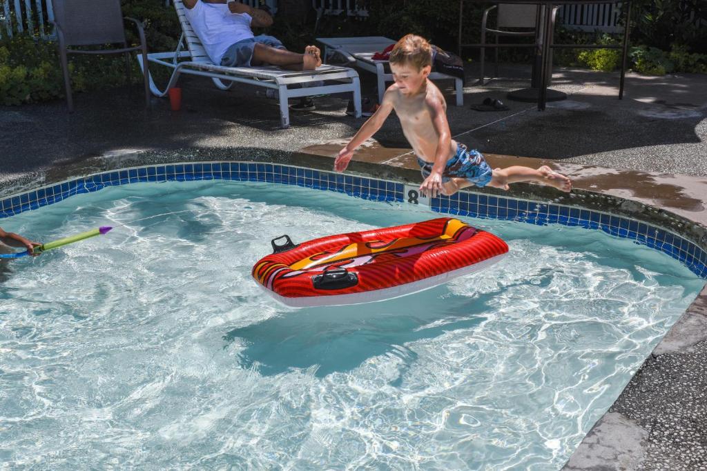 a young boy playing in a swimming pool with a raft at Thunderbird One-Bedroom Cabin 6 in Monroe