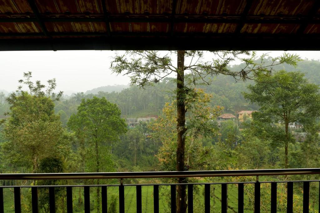 a view of a forest from a balcony at Vythiri Stream View in Vythiri