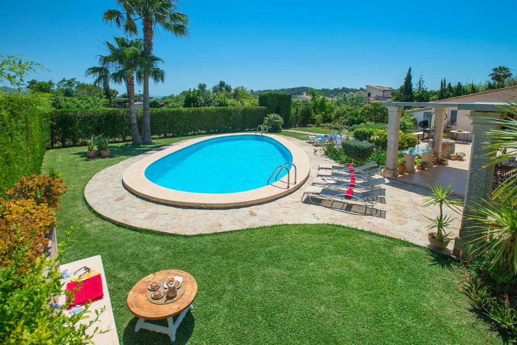 a large swimming pool in a yard with a table and a table at Owl Booking Villa Coloma - Luxury Retreat with Huge Pool in Port de Pollensa