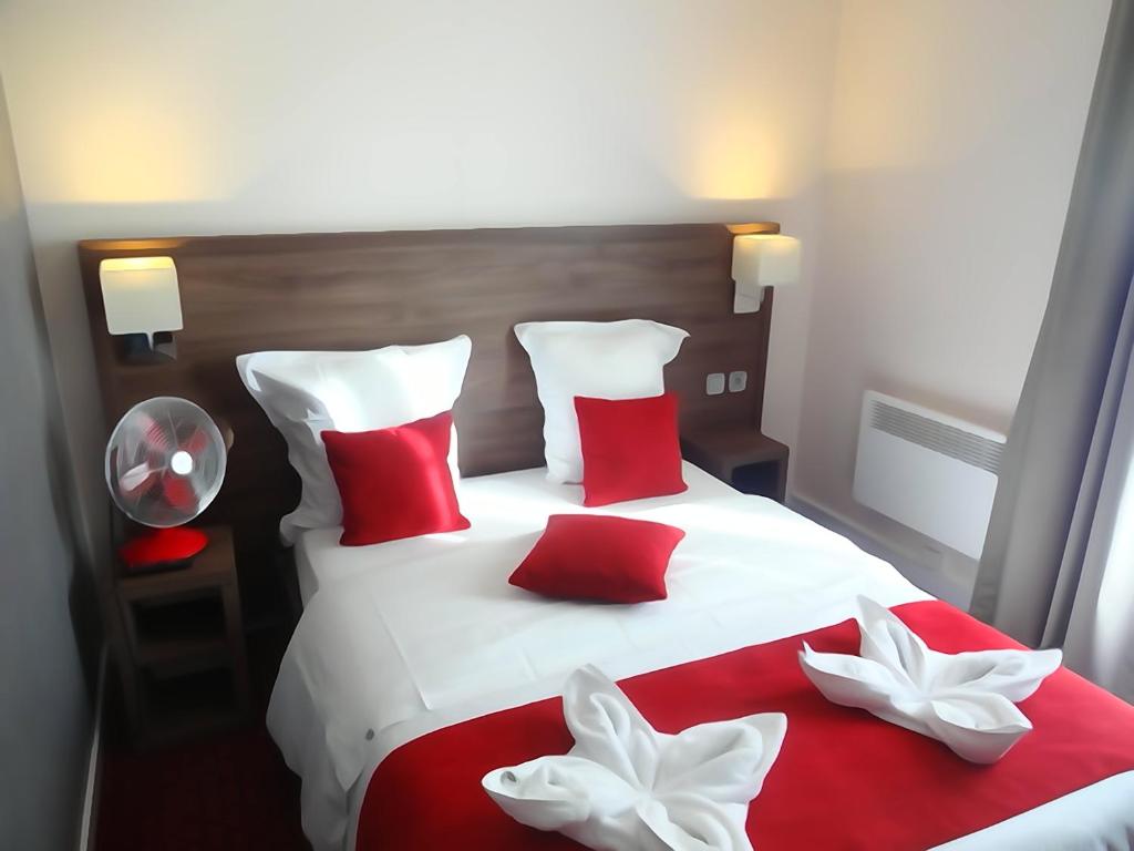 a red and white bed with red and white pillows at Hotel la Perle Montparnasse in Paris