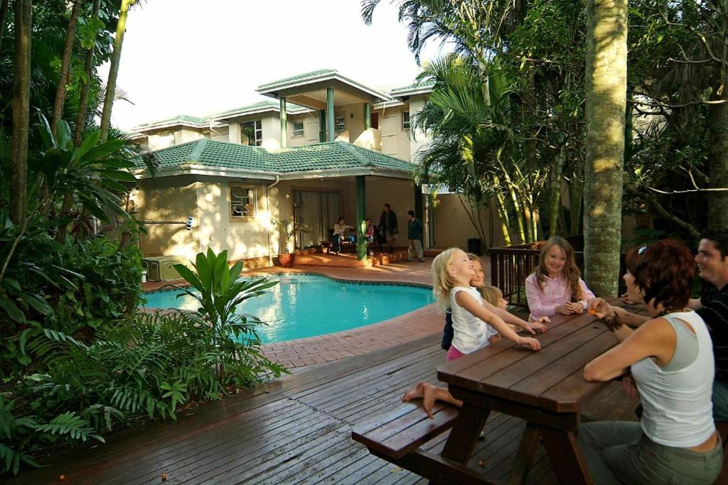 a group of people sitting at a picnic table by a pool at 42 Ramsgate palms in Margate