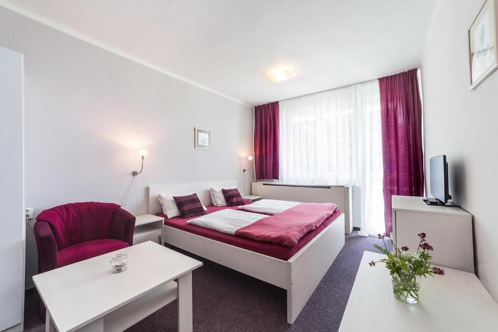 ein Hotelzimmer mit einem Bett und einem Stuhl in der Unterkunft Hotel Racek in Černá v Pošumaví