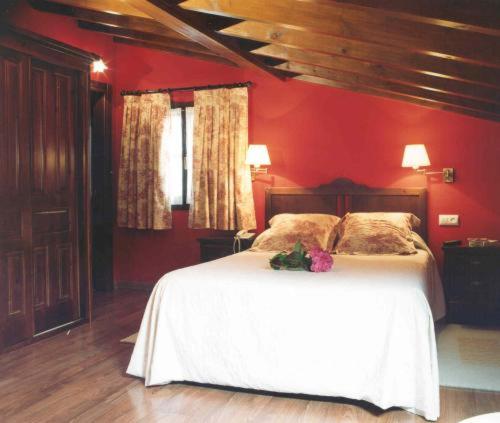 a bedroom with a white bed in a red wall at La Fonte in Naves