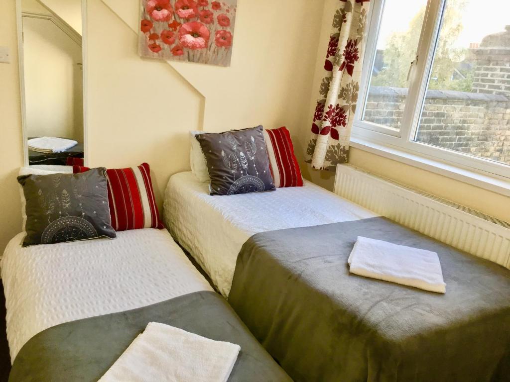 two beds in a room with a window at London Deluxe Loft Apartment with Shower in London